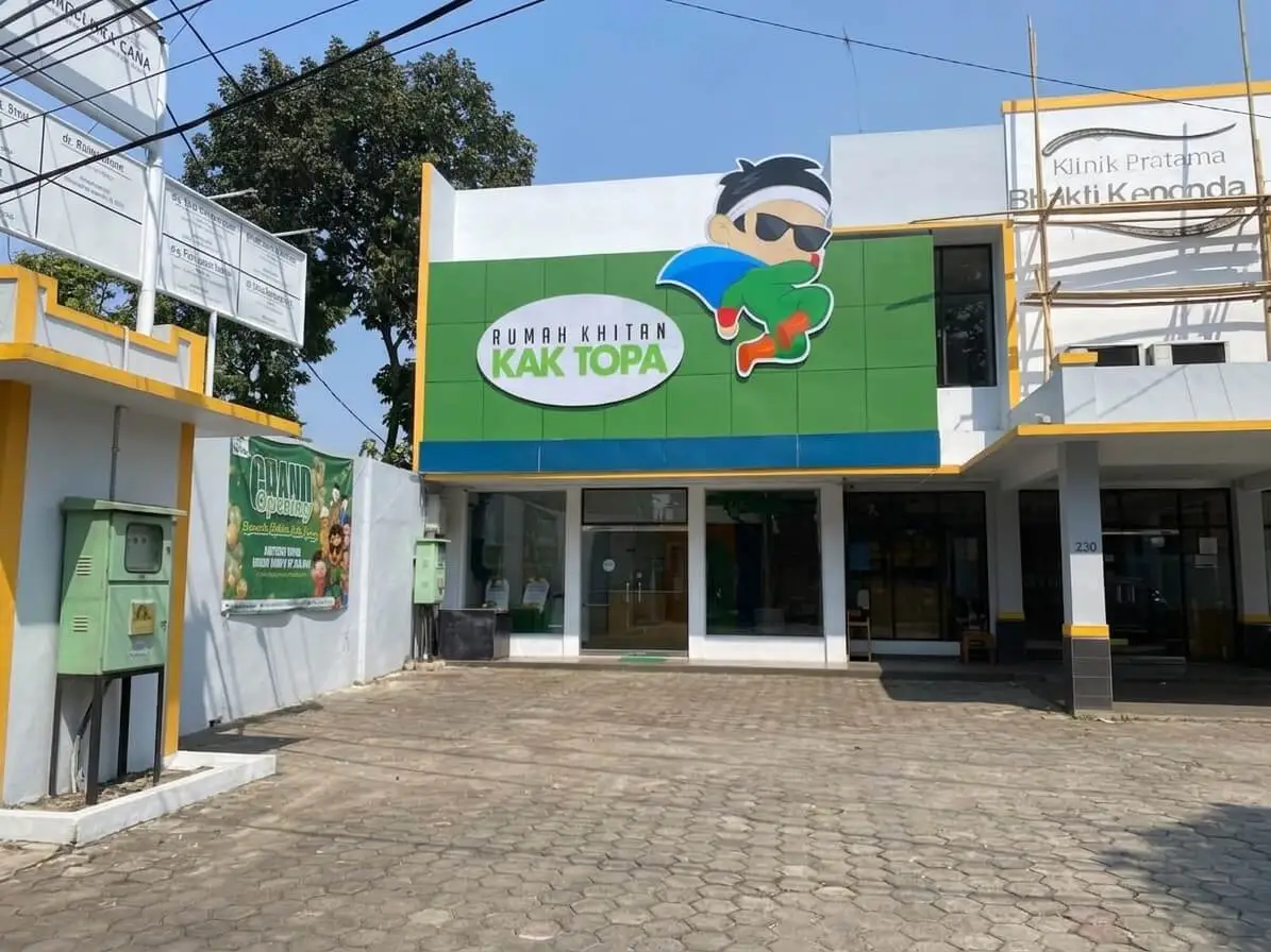 Tampak depan gedung klinik Rumah Khitan Kak Topa dengan logo karakter superhero